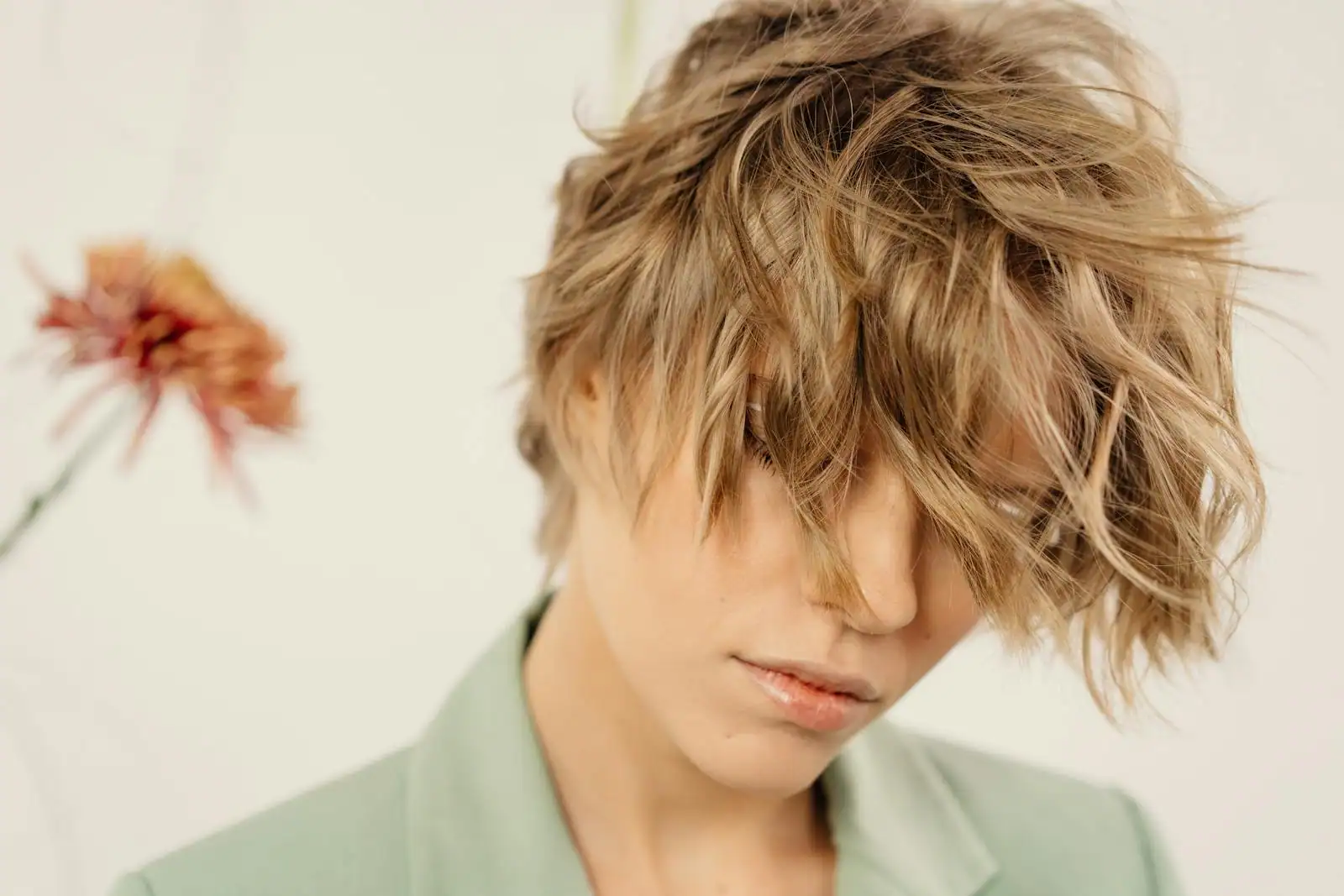 Portrait d'une femme souriante portant une coupe de cheveux courte et structurée en studio lumineux.