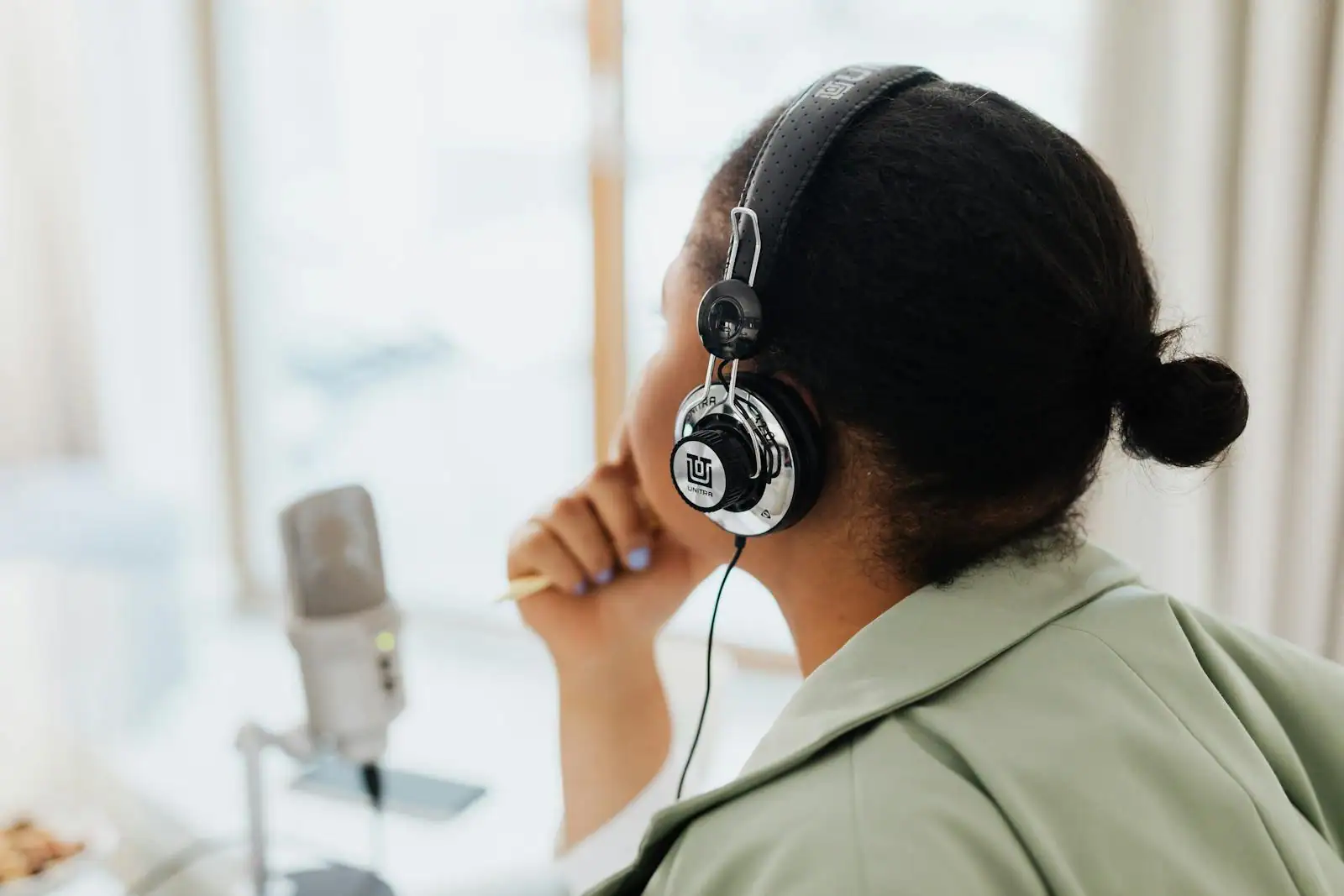 Personne écoutant la radio avec un casque audio, installée à une table près d'une fenêtre