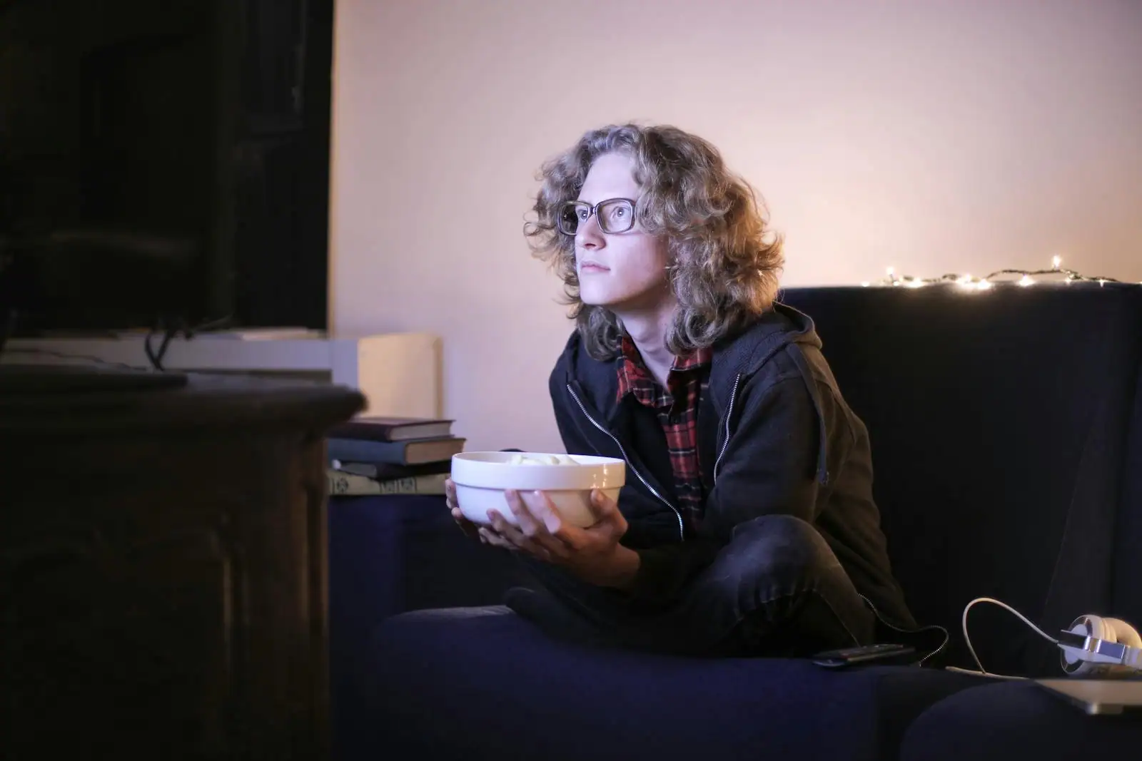 Personne regardant une série télévisée le soir sur un canapé dans la pénombre