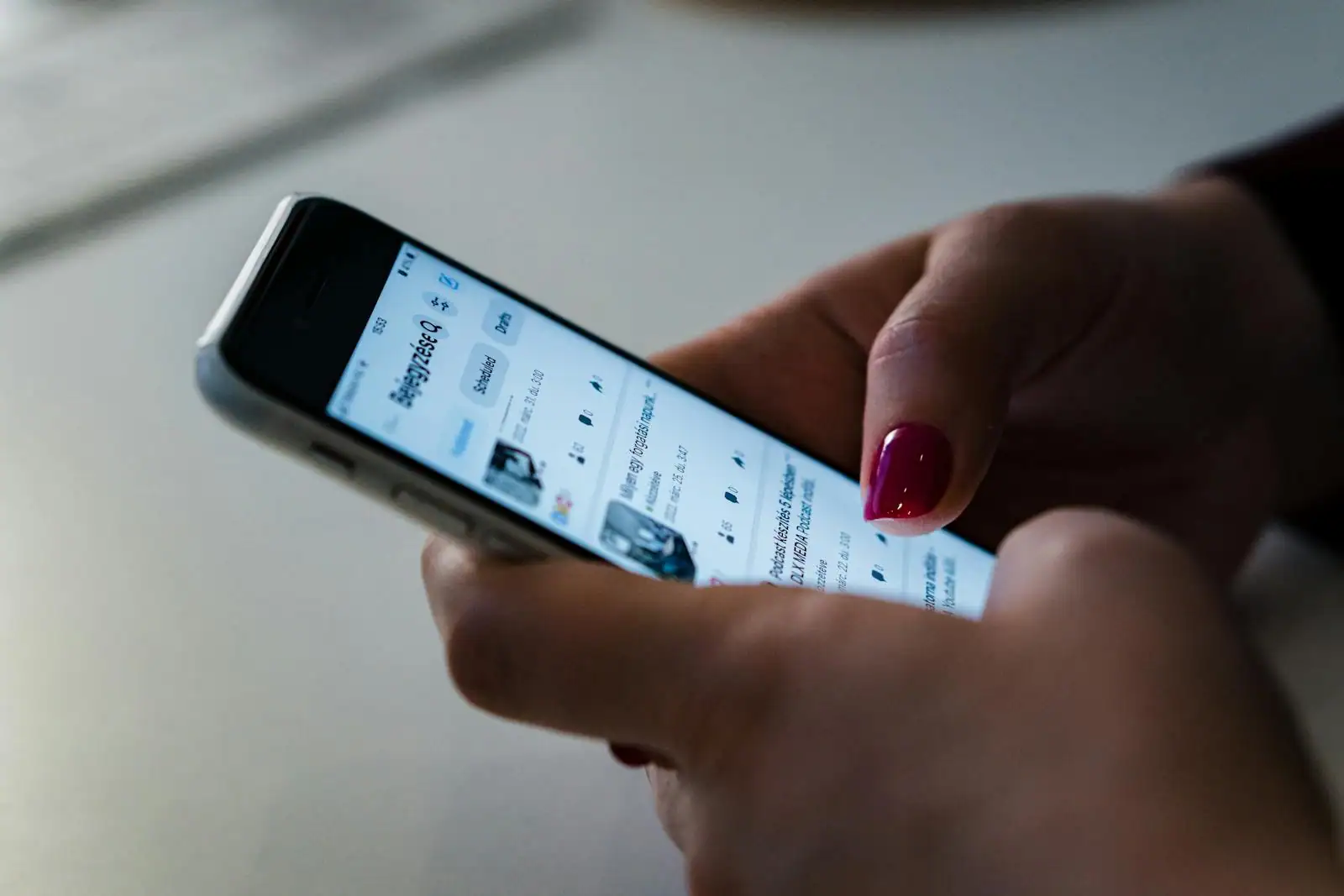 Personne tenant un smartphone qui fait défiler une application vidéo, écouteurs autour du cou.