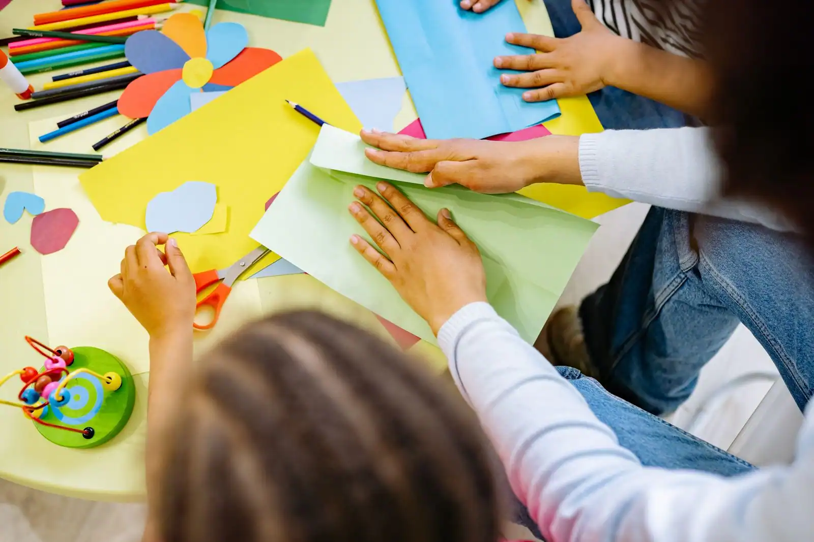 Enfants réalisant un bricolage avec du papier coloré sur une table