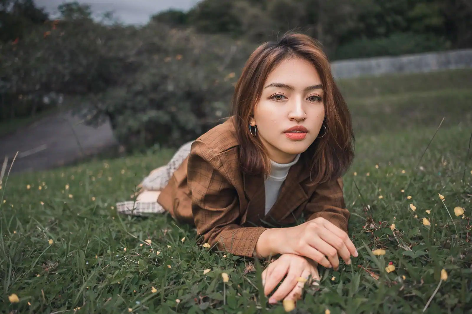 Jeune femme aux cheveux châtains à reflets chauds auburn, portrait en extérieur dans l'herbe