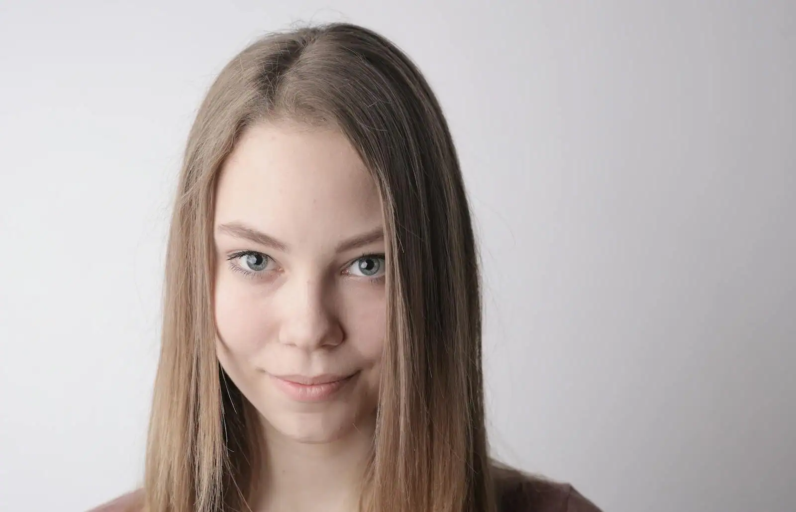 Portrait d'une jeune femme aux longs cheveux lisses et brillants, sur fond clair