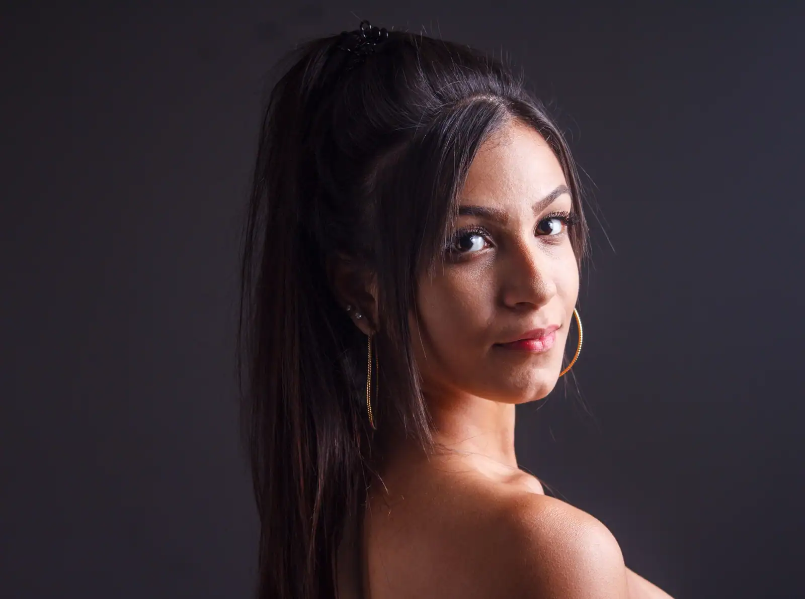 Portrait studio d'une femme aux longs cheveux bruns foncés, lisses et brillants.