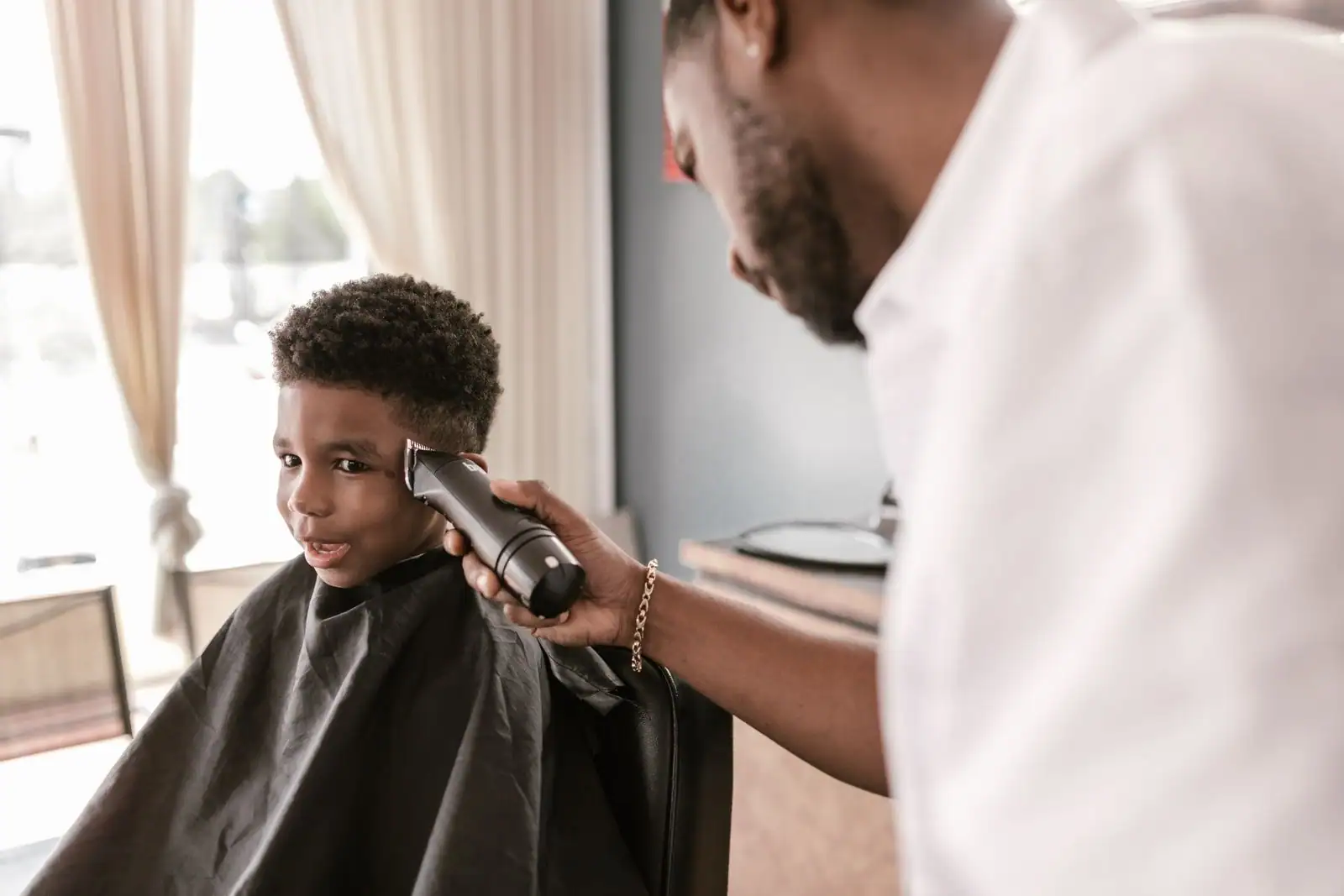 Un jeune garçon se fait couper les cheveux à la tondeuse par un coiffeur dans un salon