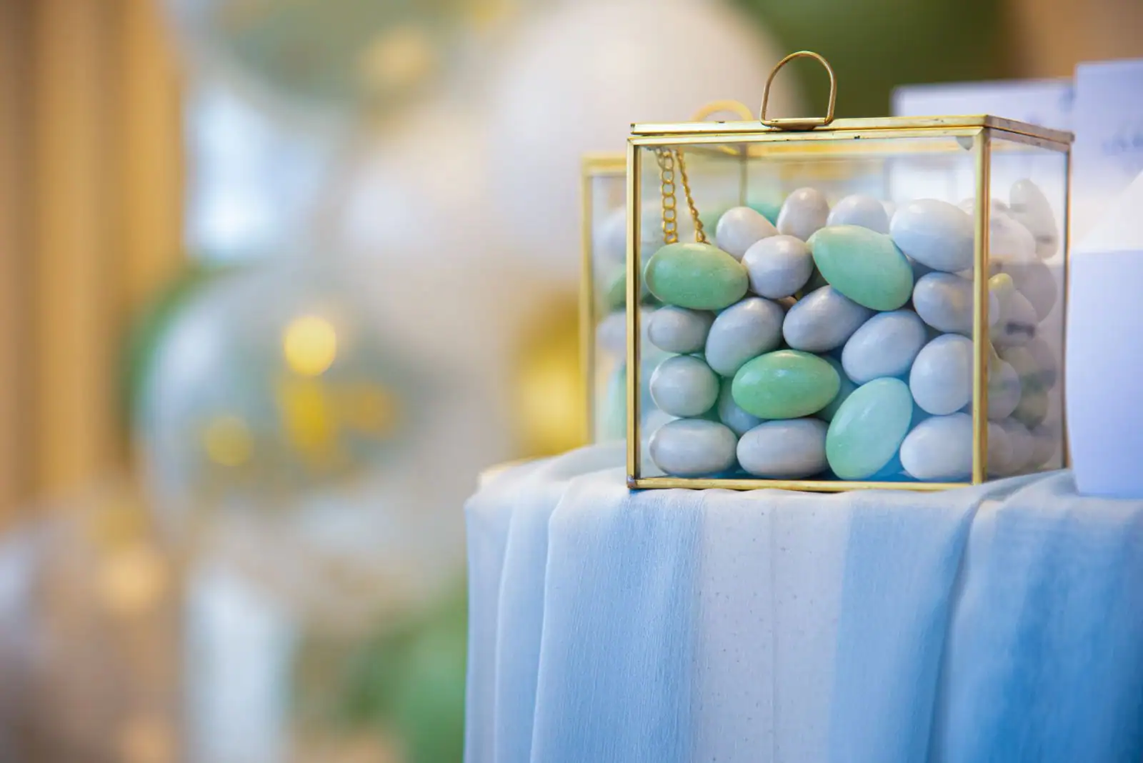 Dragées aux amandes de teintes pastel dans un coffret en verre, lors d'une cérémonie