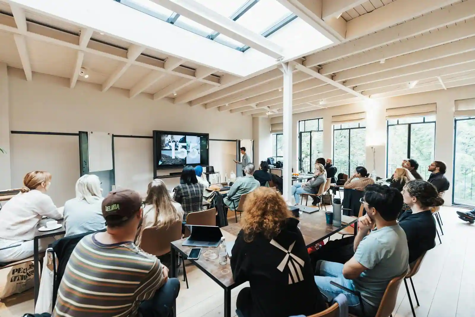 Groupe d'adultes attentifs assistant à une présentation dans une salle lumineuse