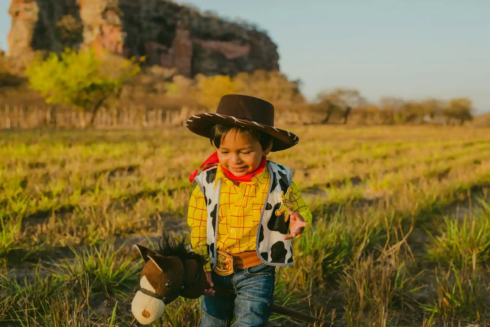 Enfant galopant dans un champ avec un cheval-bâton en extérieur