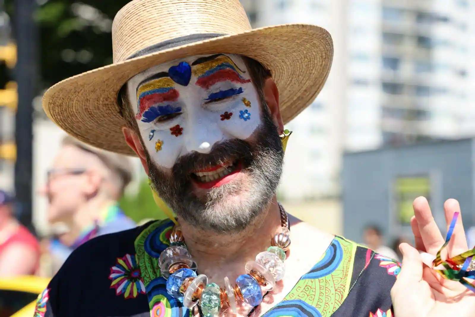 Un homme souriant arbore un maquillage de visage coloré et festif, dans l'esprit du clown