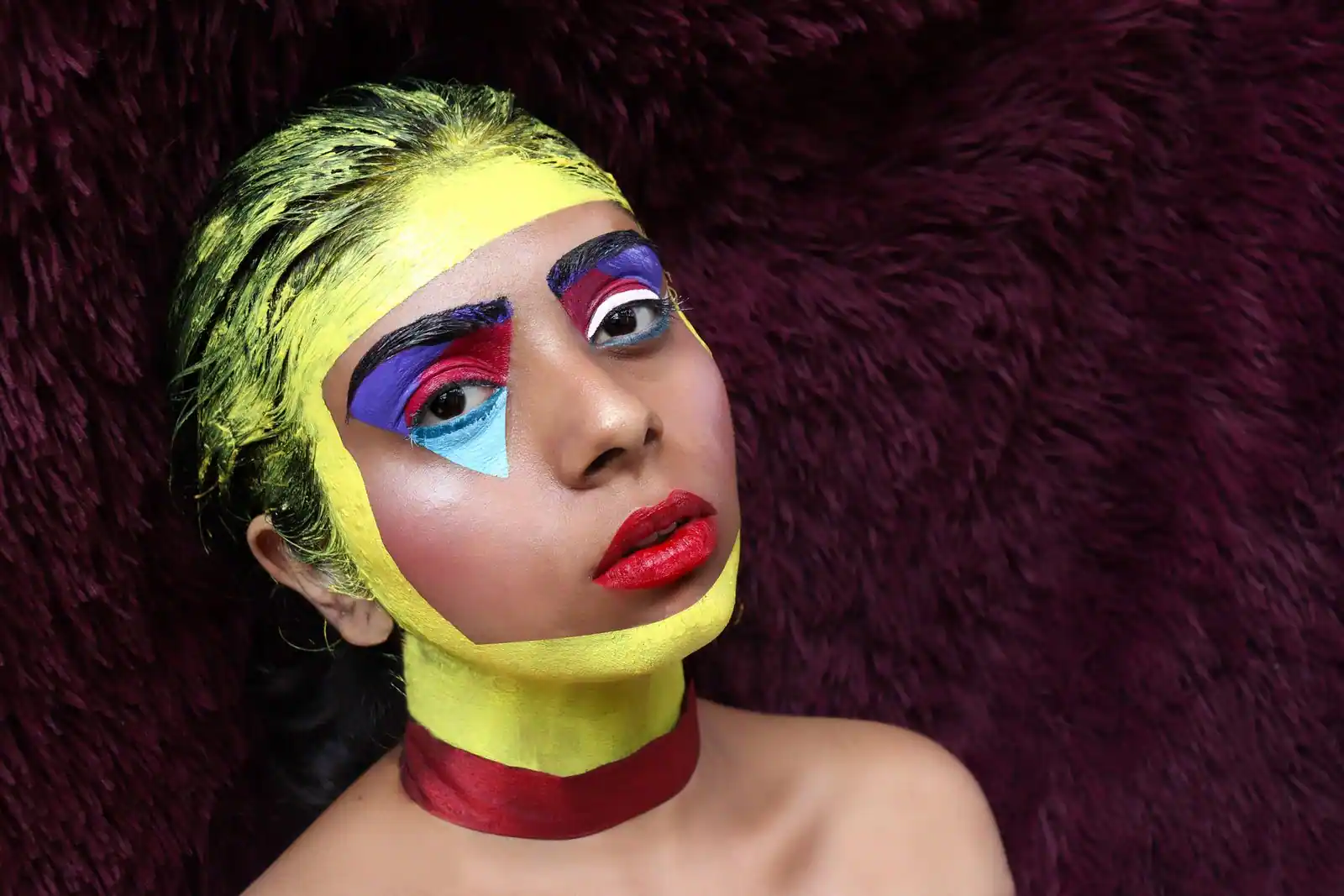 Portrait d'une femme au maquillage artistique très coloré, visage peint et fards bleu et rouge autour des yeux