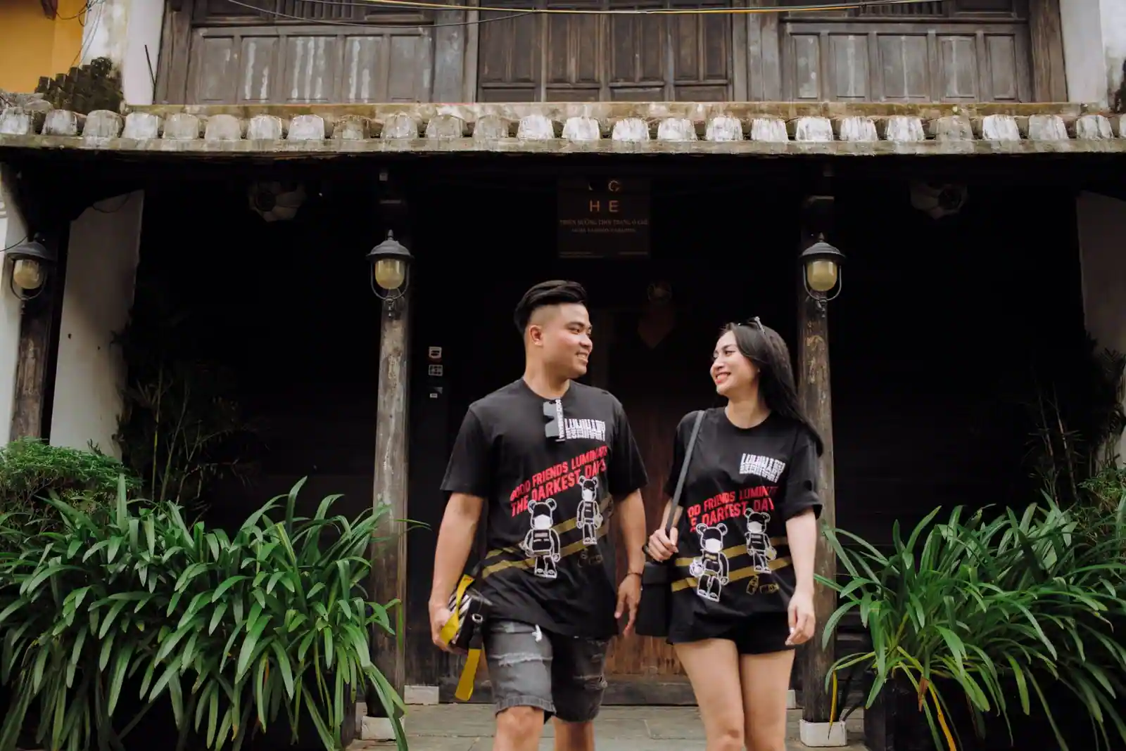 Un couple souriant se promène côte à côte devant une maison ancienne lors d'une escapade du week-end