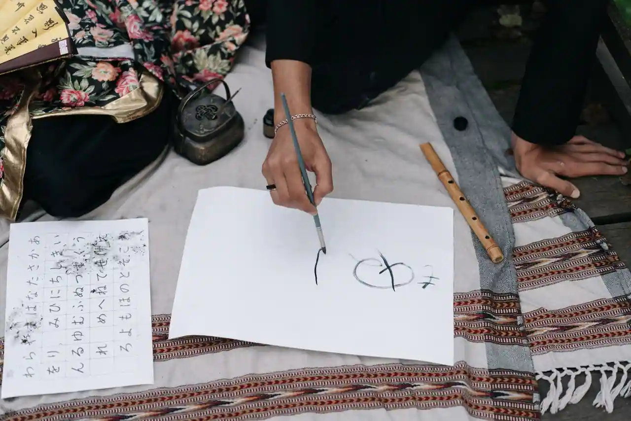 Main tenant un pinceau de calligraphie japonaise traçant des caractères à l'encre noire sur du papier