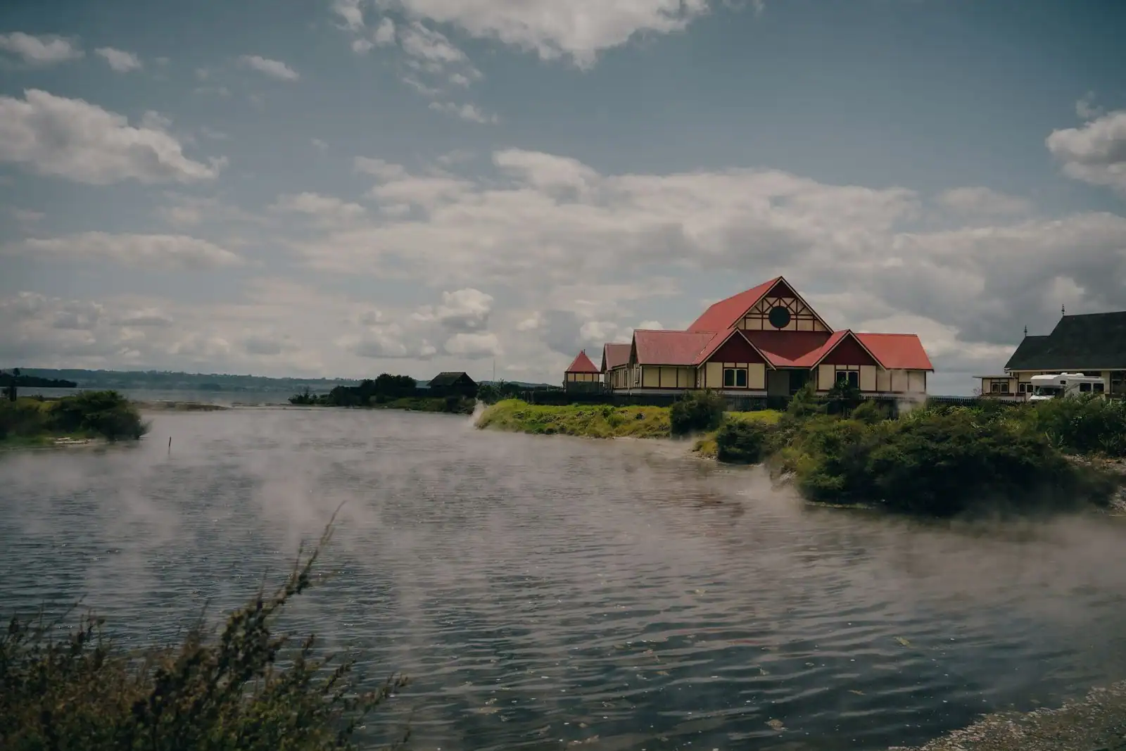 Village maori au bord d'un lac de Rotorua en Nouvelle-Zélande, entouré de vapeur géothermique