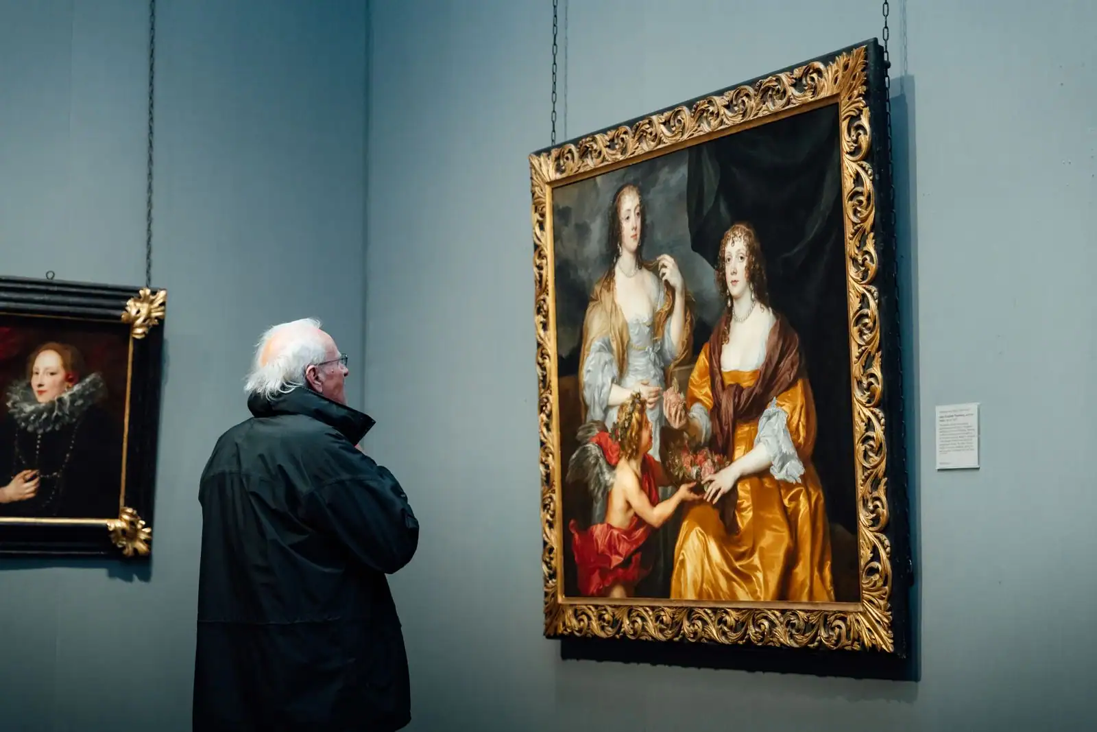 Visiteur observant des tableaux anciens encadrés dans une salle de musée d'art