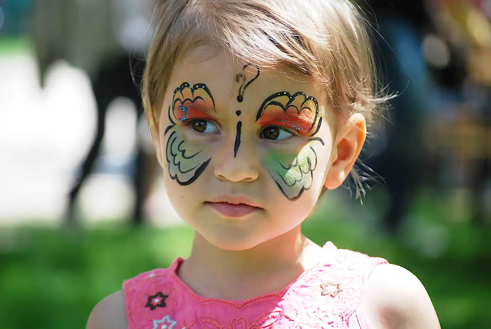 Maquillage papillon peint autour des yeux d'une enfant, ailes symétriques contourées et antennes