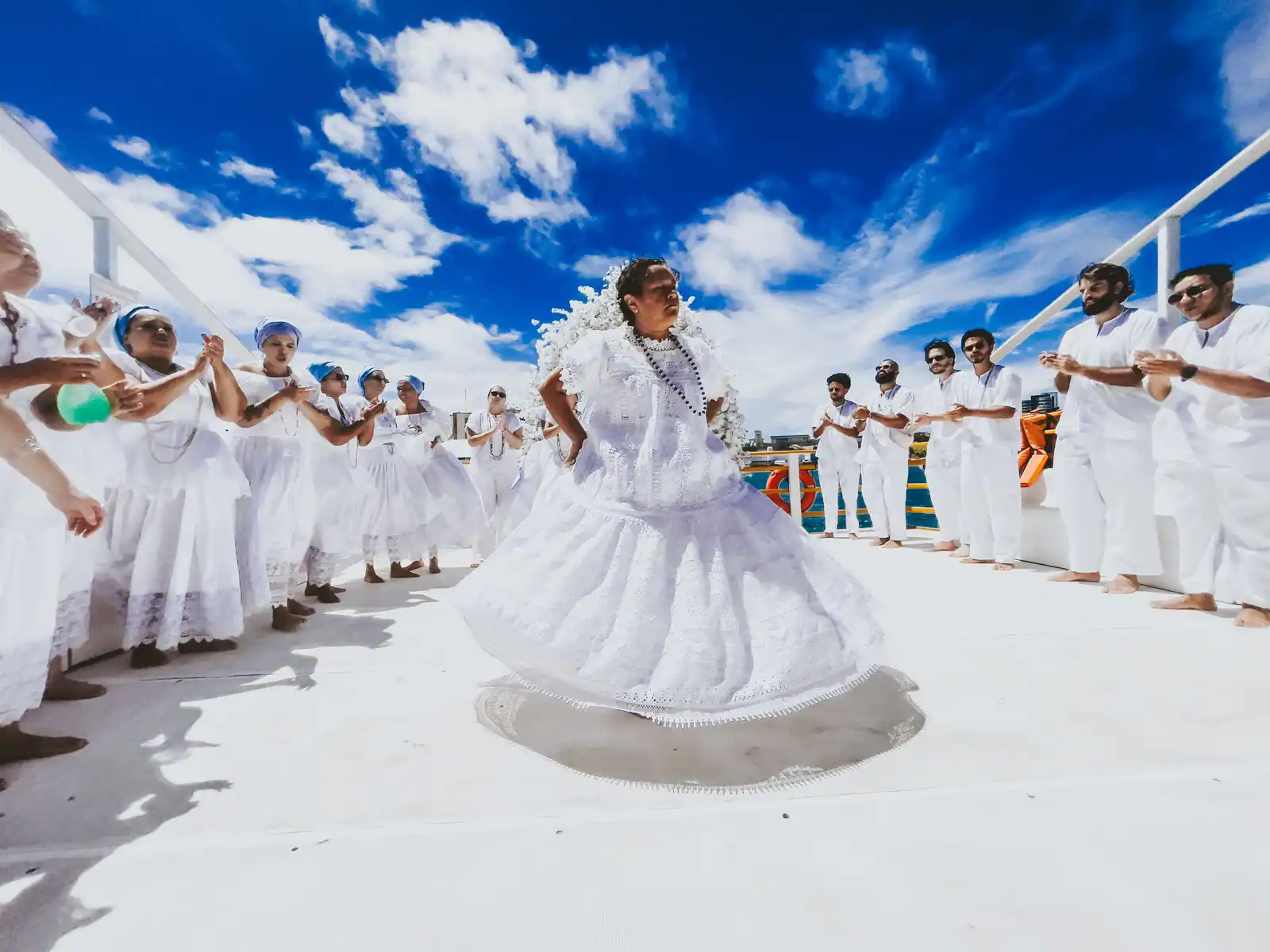 Danseuse en robe blanche tournoyant au centre d'un cercle de participants vêtus de blanc, au Brésil