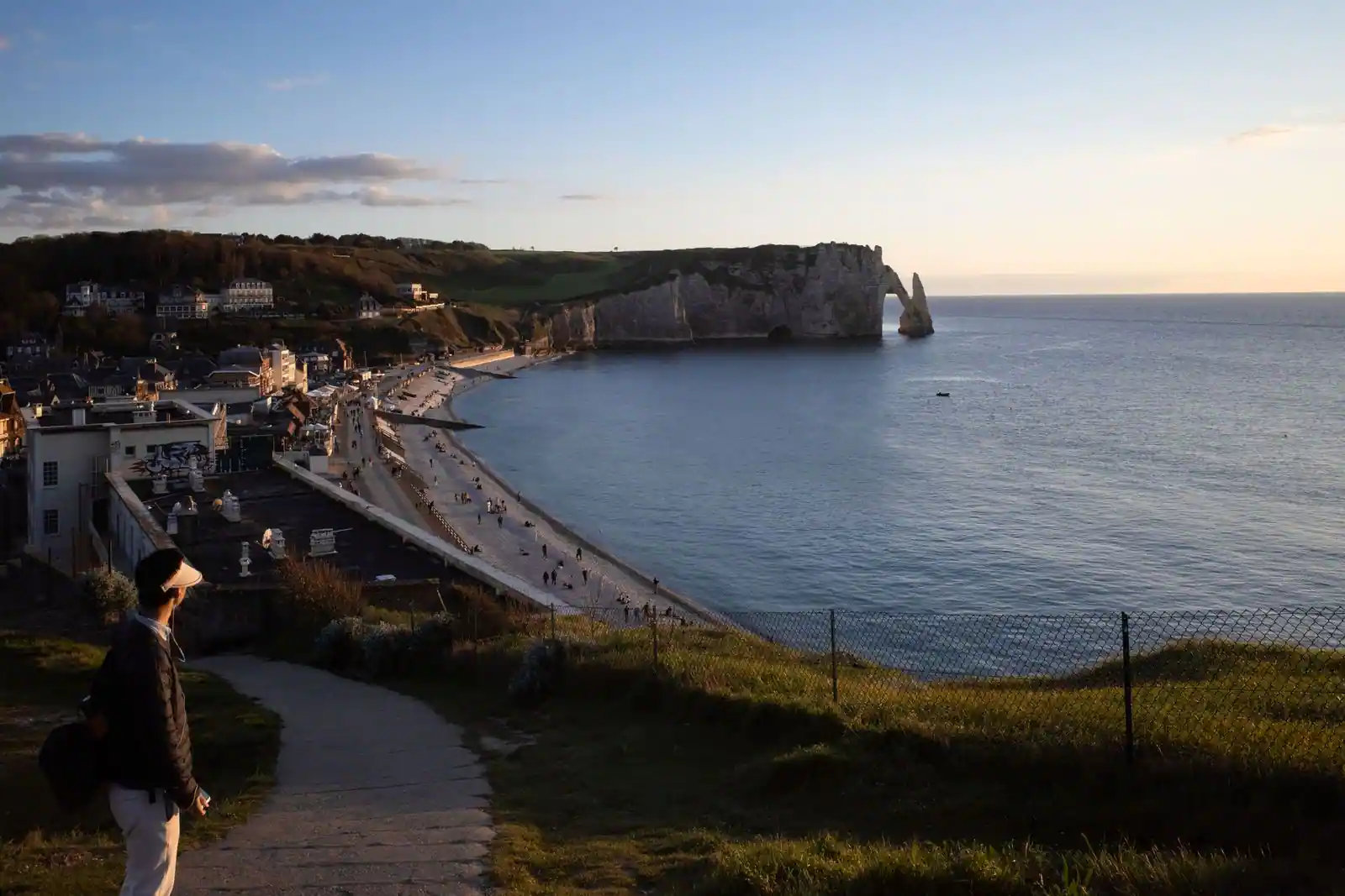 Falaise et arche d'Étretat au coucher du soleil, avec la plage de galets et le village en contrebas
