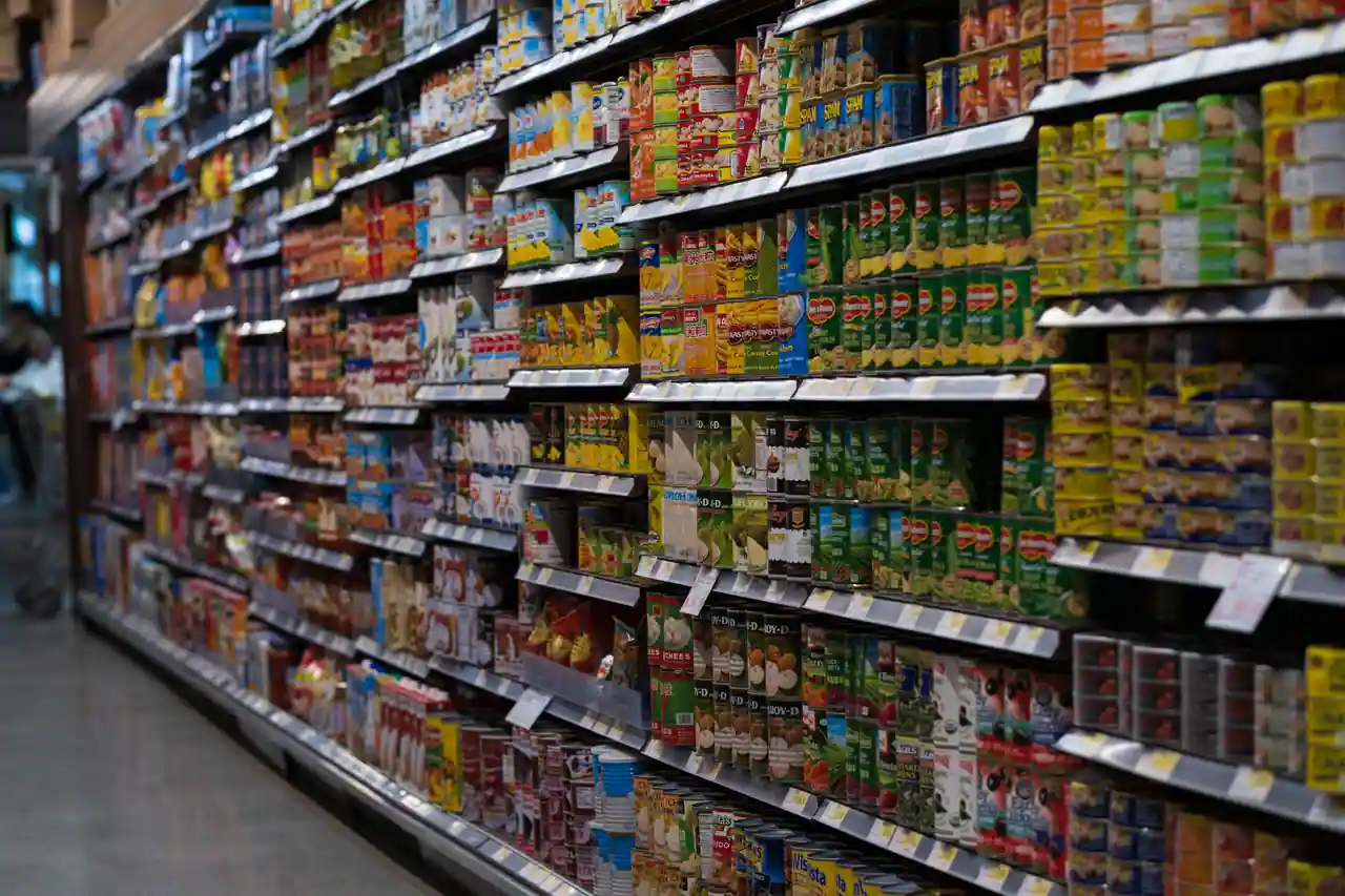 Rayon de supermarché rempli de conserves et produits d'épicerie, illustrant la grande distribution.
