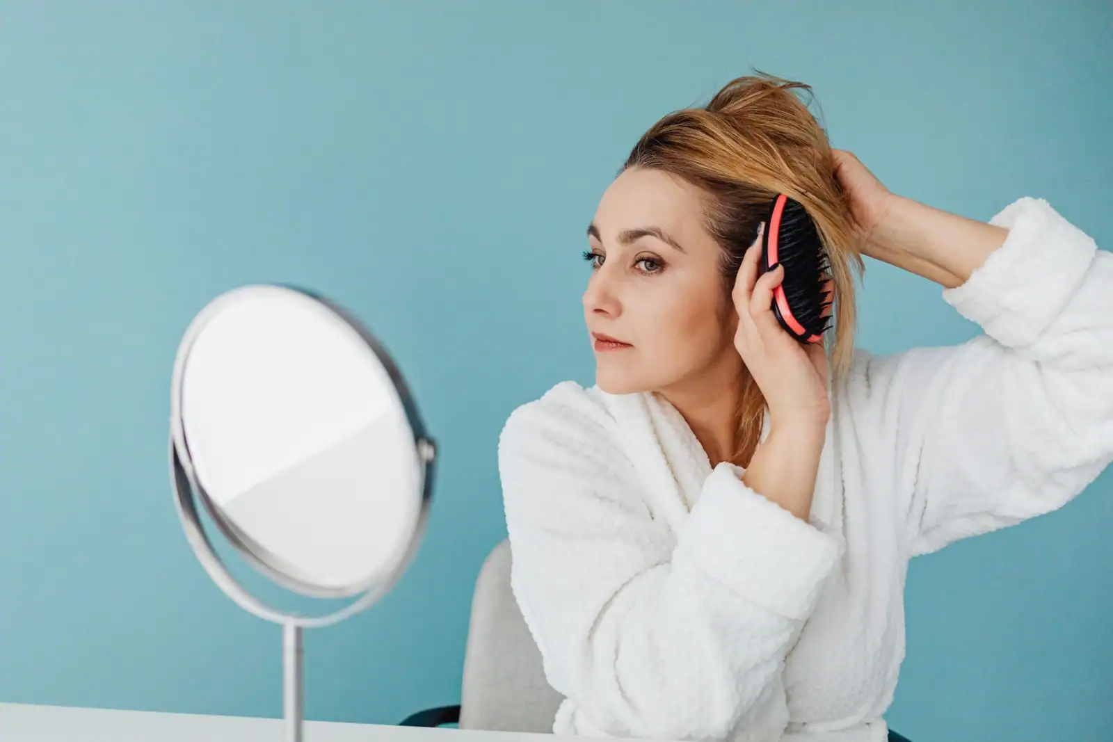 Une femme aux cheveux longs et lisses de dos, tenant ses pointes entre ses mains